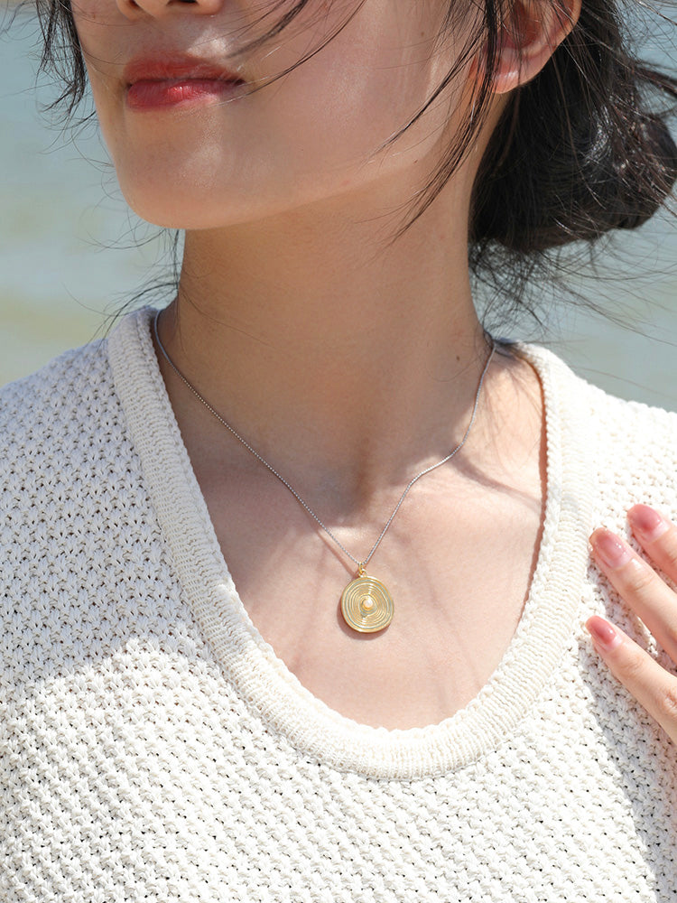 A delicate and simple gold coin necklace with an annual wheel